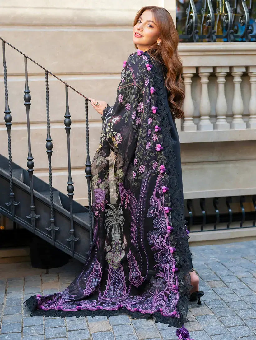 Woman wearing a black embroidered dress with pink floral details on a staircase.